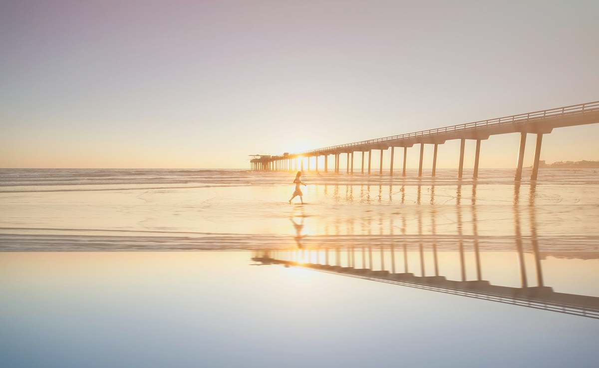 beach person walking on sea near bridge during daytime san diego